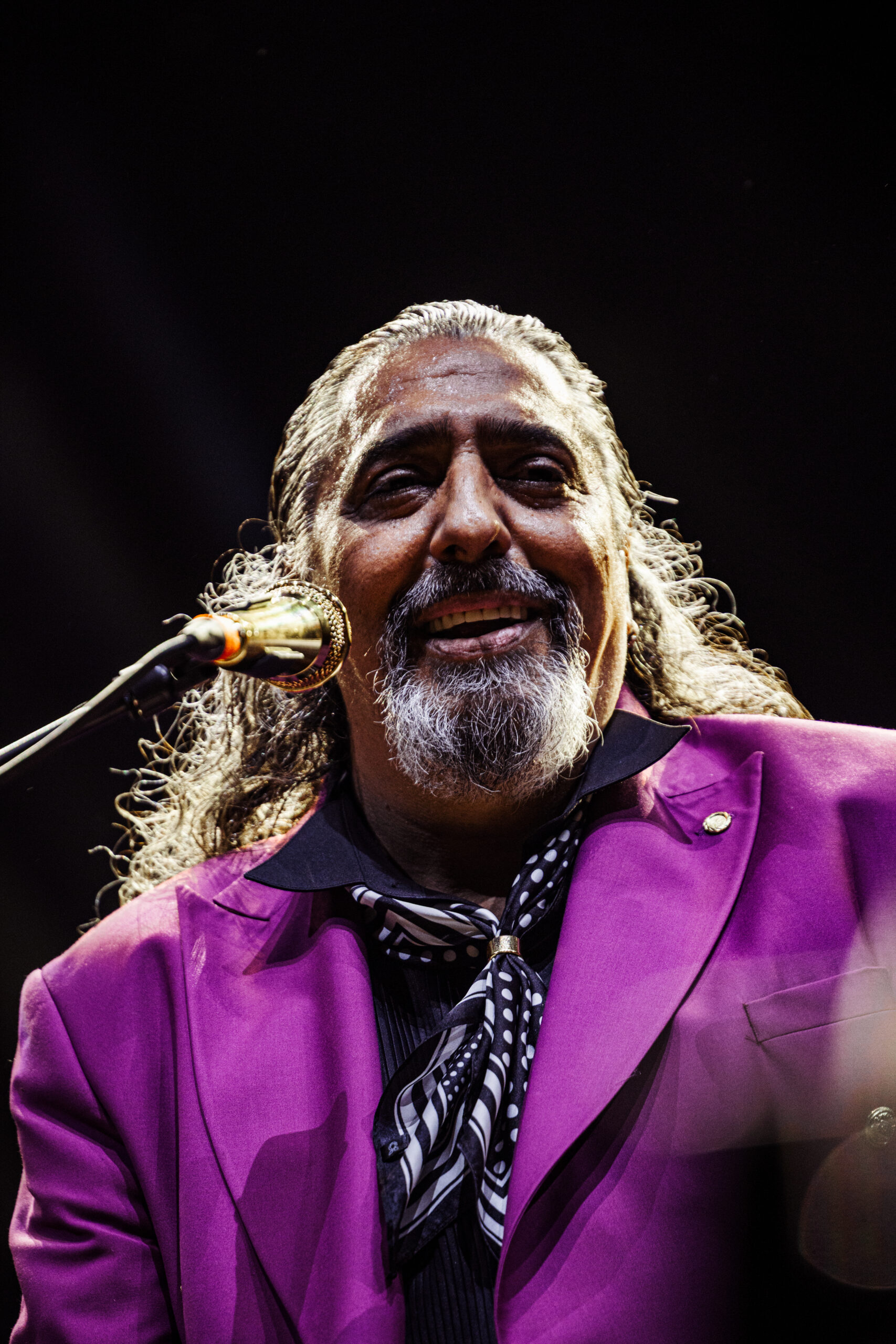 Retrato de Diego El Cigala cantando ante el micrófono con traje morado