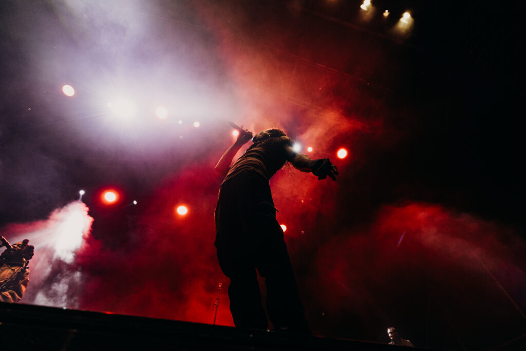 Cantante a contraluz entre humo rojo y focos en el escenario del WOMAD
